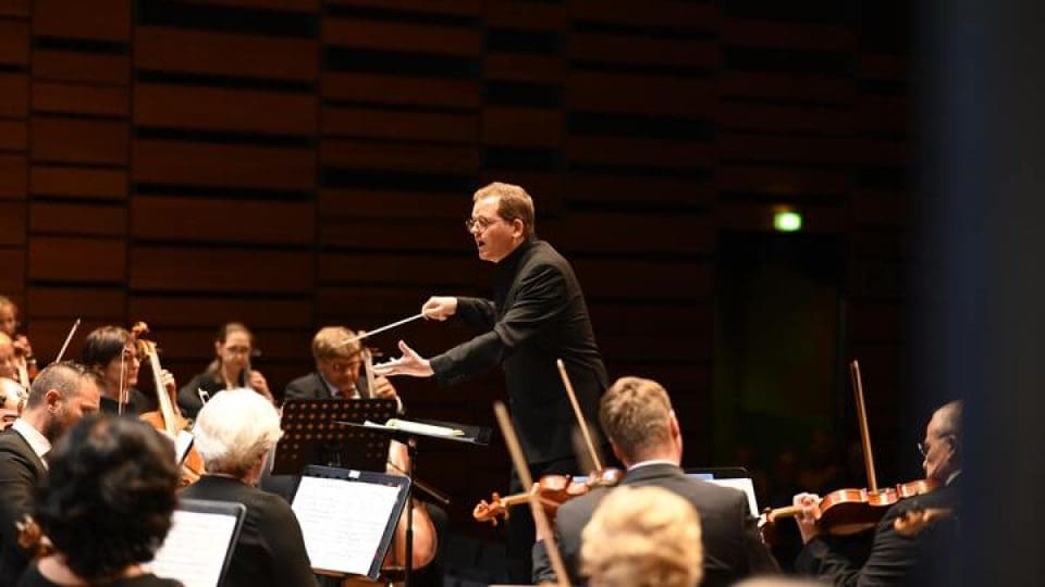 Man in glasses leading an Orchestra