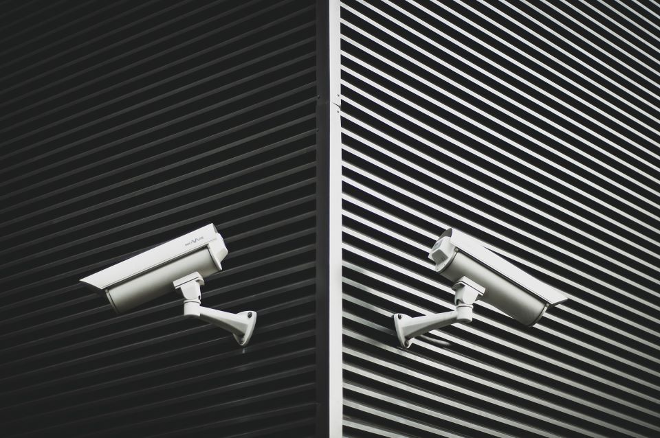 Two security cameras facing opposite directions on the corner of a building.