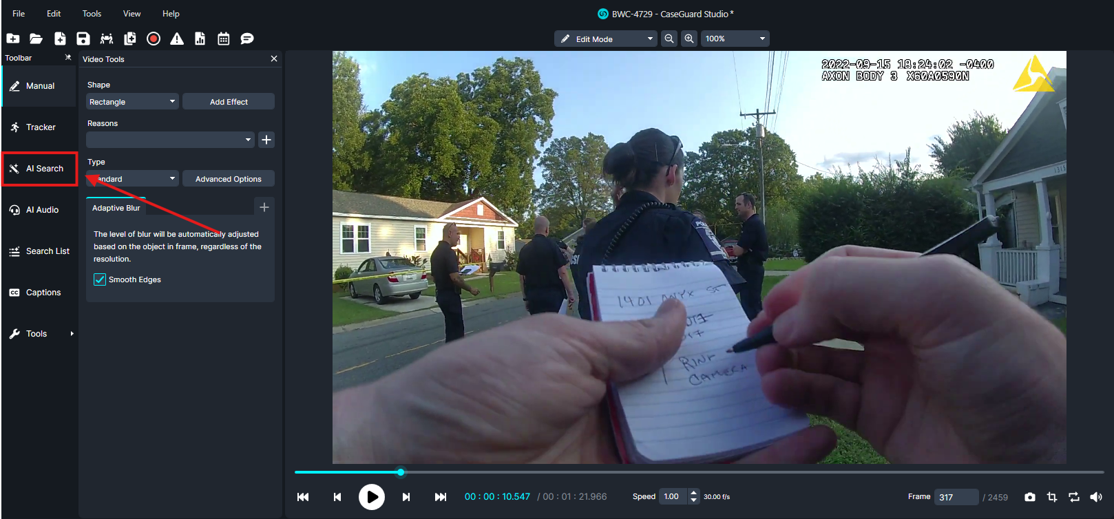 Video frame showing police officers on a suburban street; a person in the foreground writes notes in a small notebook held up close to the camera.